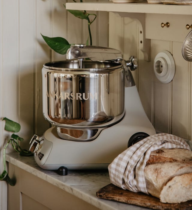 A kitchen counter with an Ankarsrum assistent and a loaf of bread on it.