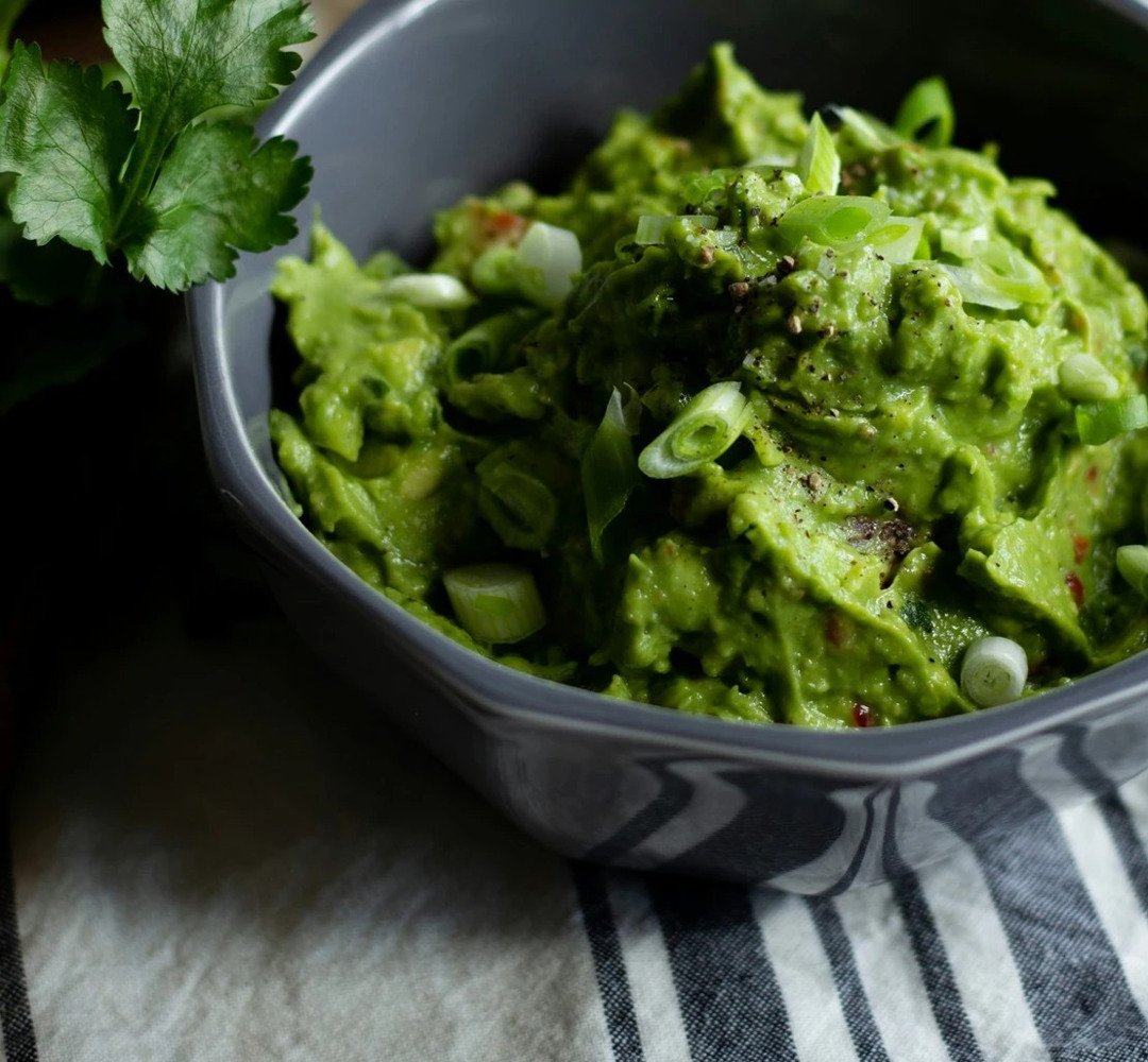 En skål med guacamole med en garnering på toppen.
