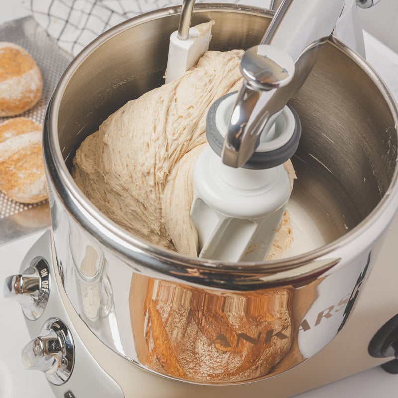 A loaf of bread and a ankarsrum assistent on a counter.