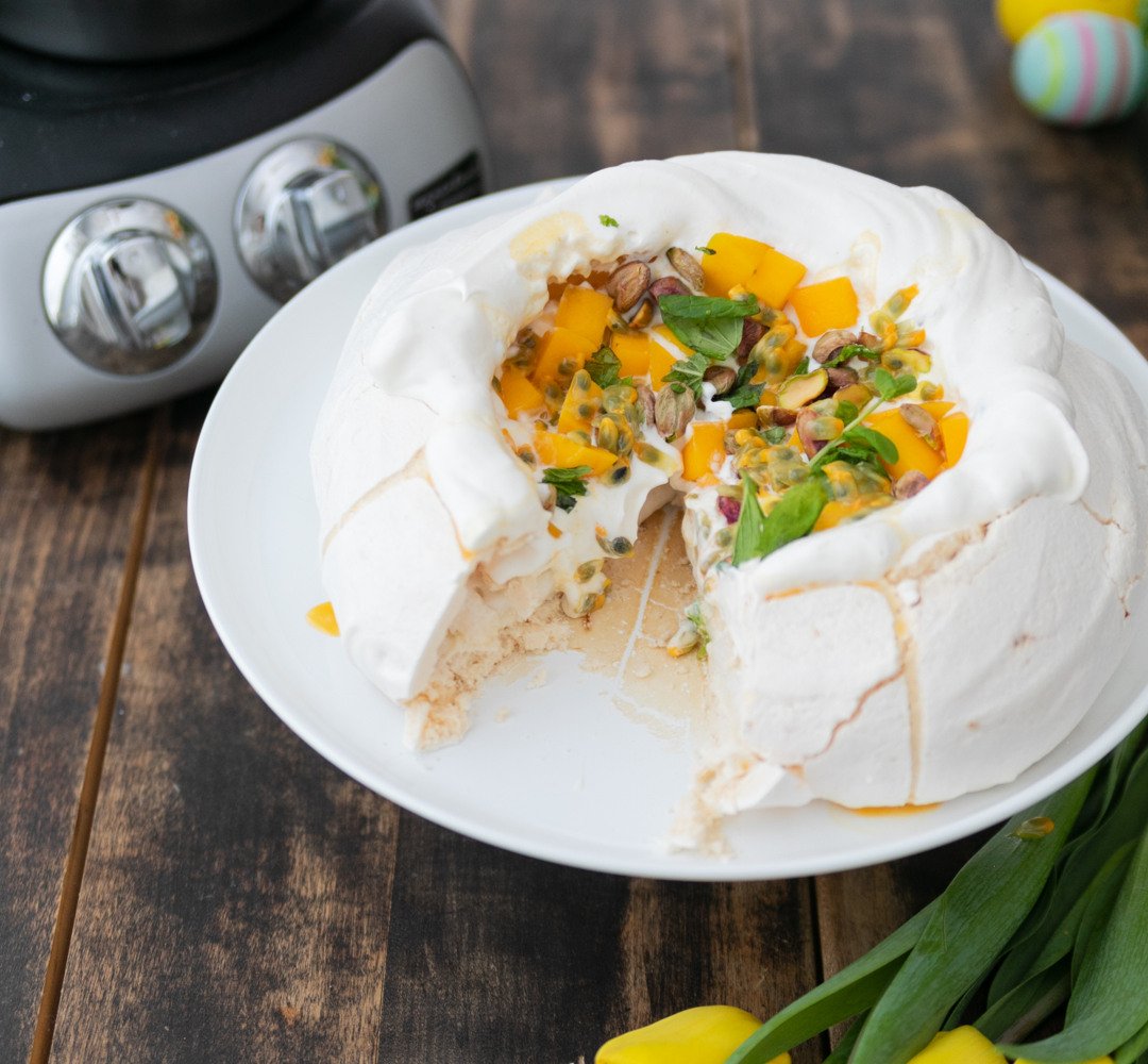 A white plate topped with a pavlova next to yellow flowers.