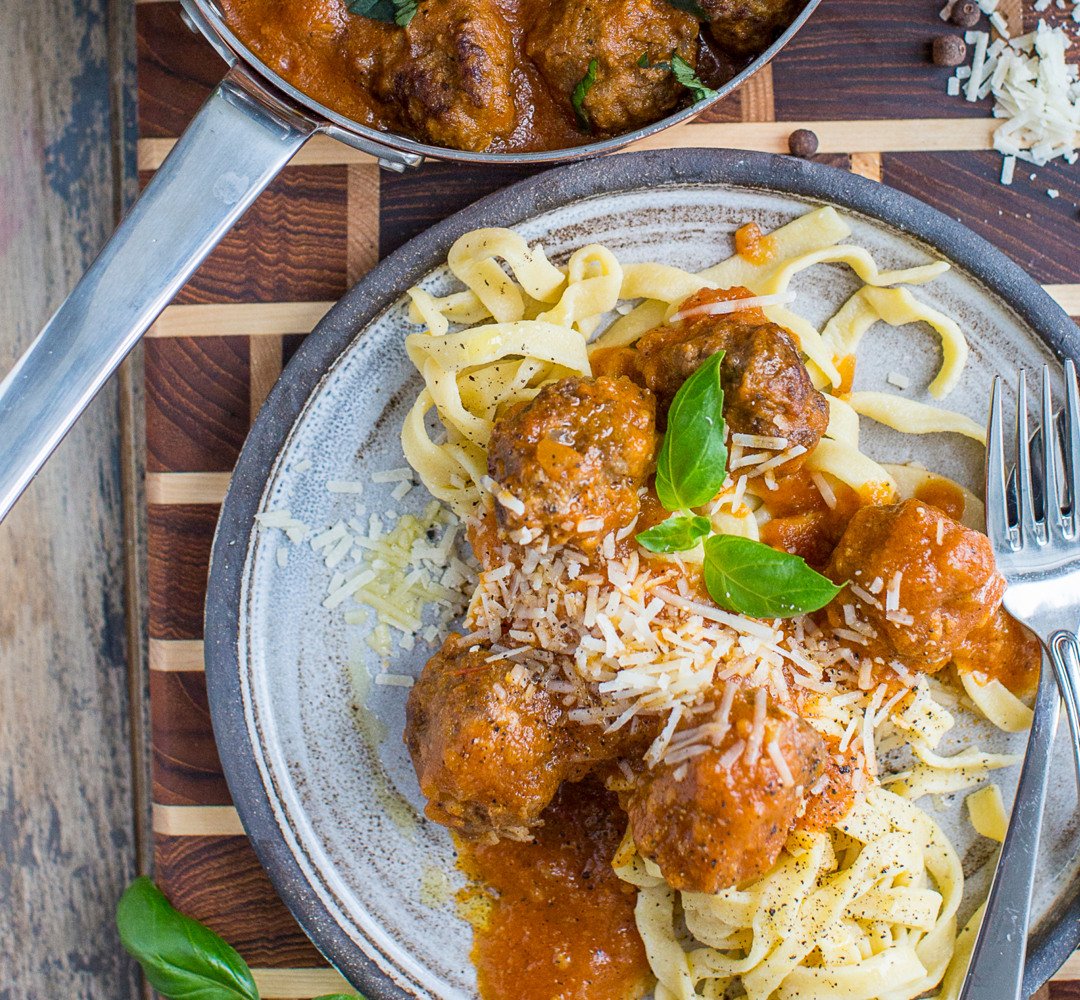 En tallrik spaghetti och köttbullar på ett träbord.