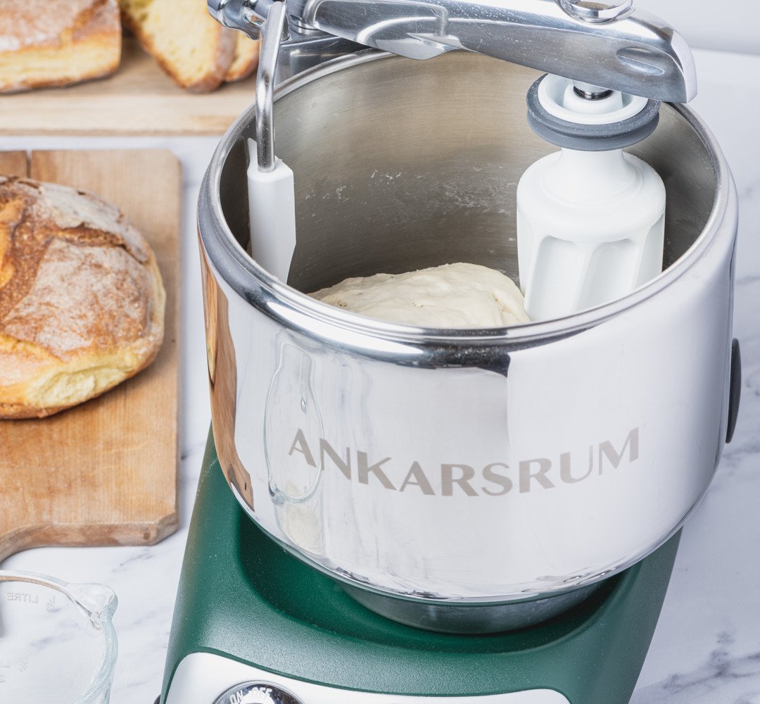 Ankarsrum assistent in forest green, sitting on top of a counter. Baking bread