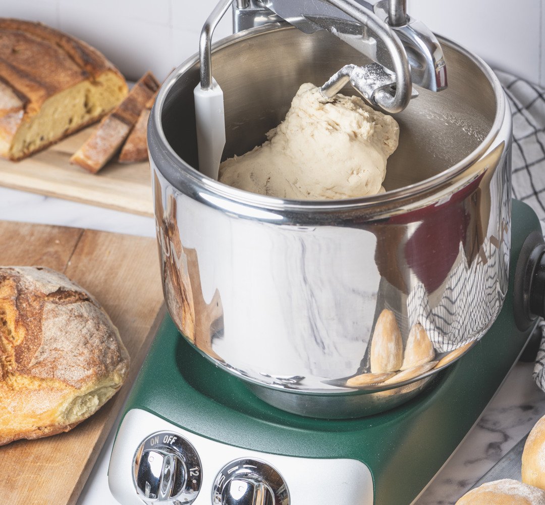 Ankarsrum assistent in forest green, sitting on top of a counter. Baking bread