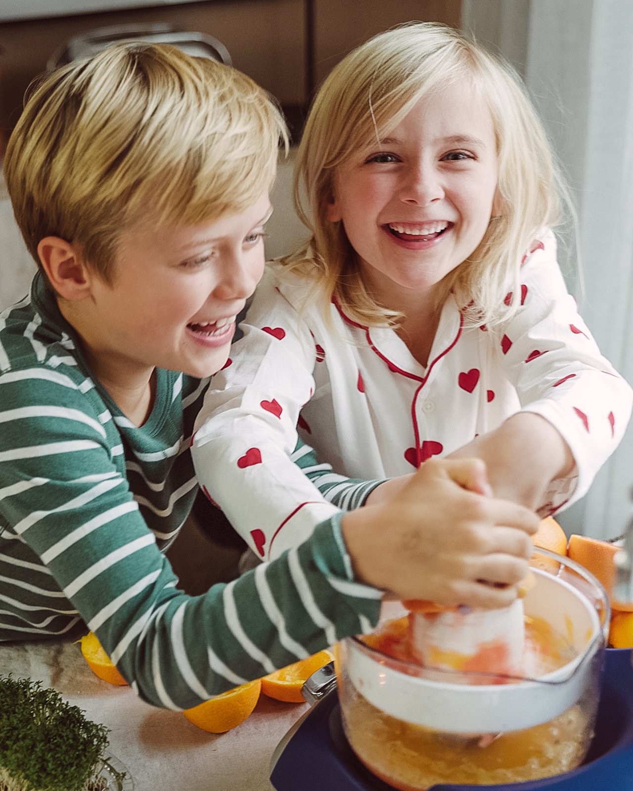 En pojke och en flicka som gör apelsinjuice tillsammans.