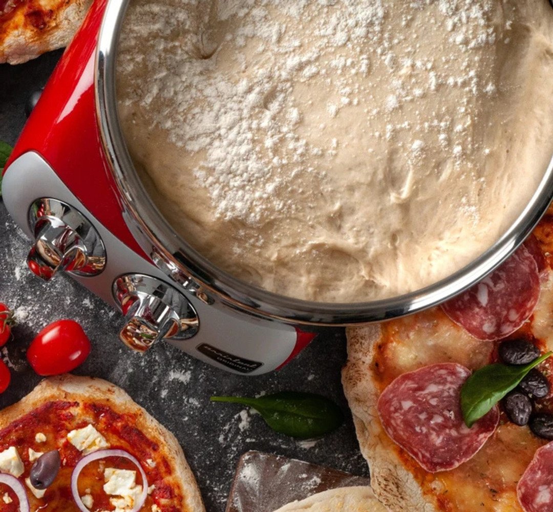 Förberedd pizzadeg i Ankarsrum Assistent på en köksbänk, med nygräddade pizzor vid sidan om.