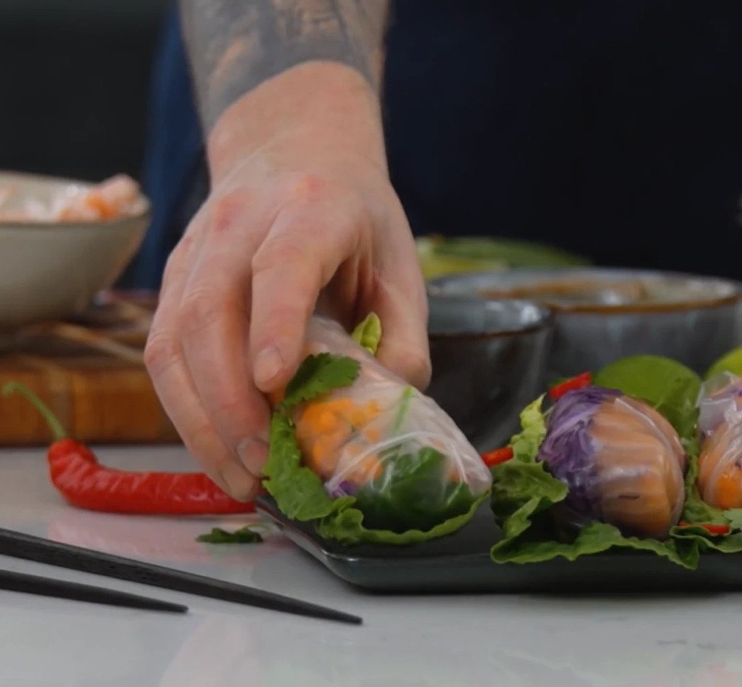 En person som förbereder vietnamesiska vårrullar på en skärbräda.