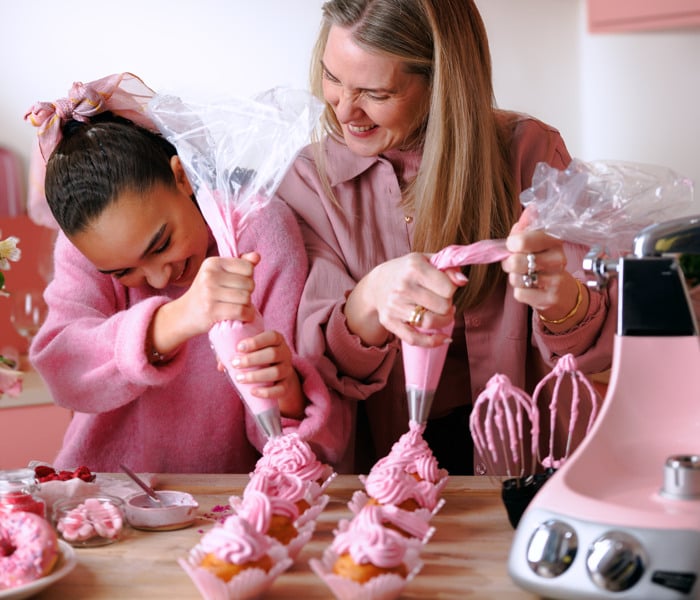 En kvinna och ett barn bakar cupcakes.