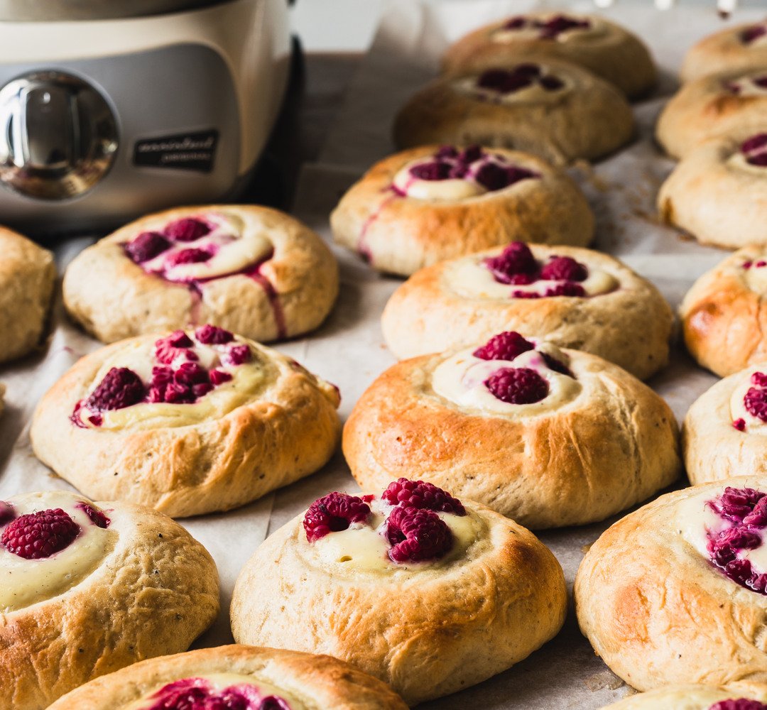 Ett bord med en bakplåt fylld med nygräddade bullar.