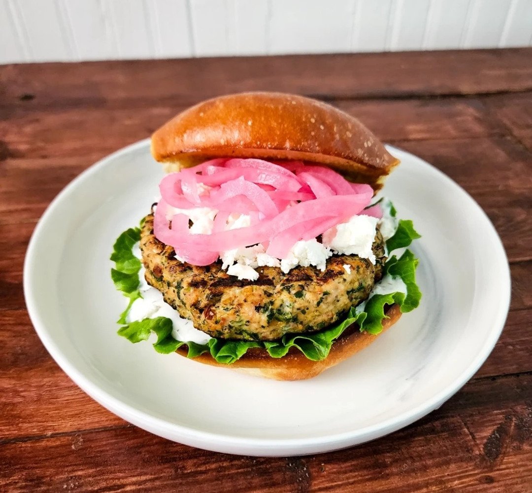 A burger with onions and lettuce on a white plate.