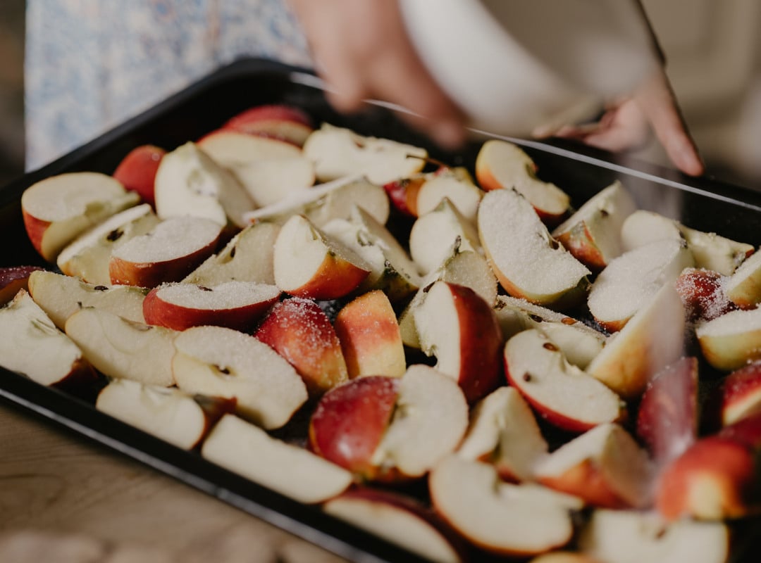 A baking tray with red apple wedges.