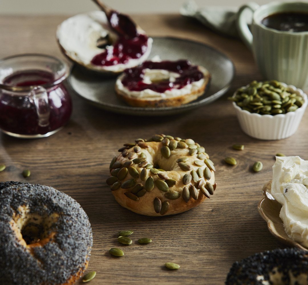 Ett träbord med bagels toppade med cream cheese och sylt.