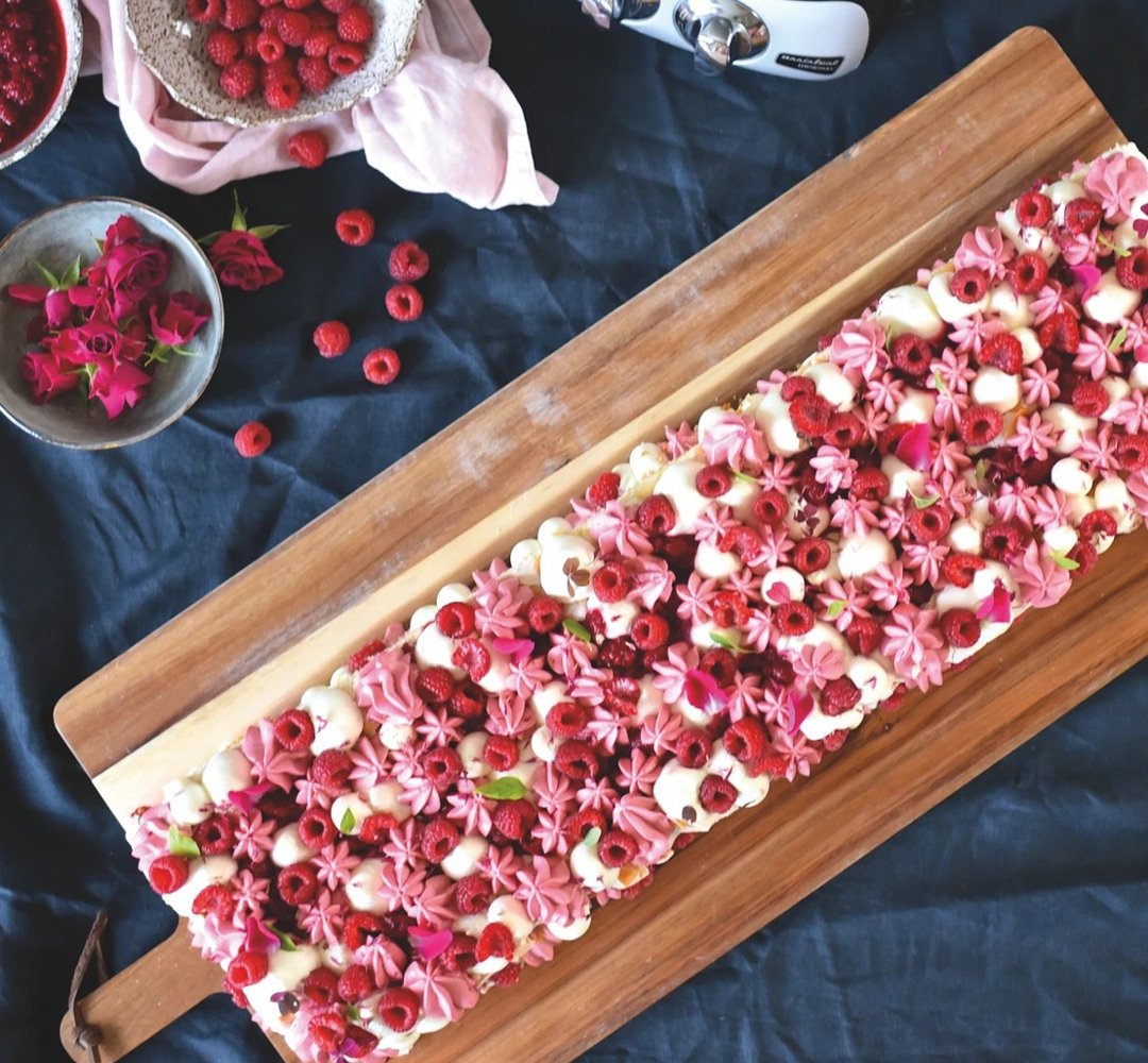 Pinocchio cake with whipped raspberry panna cotta. On a wooden cutting board.