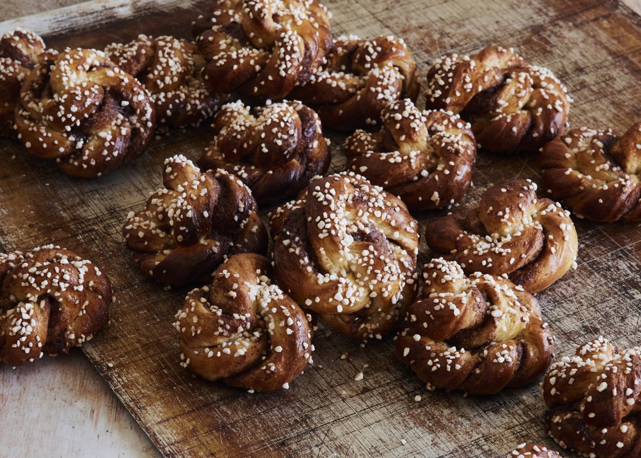 A wooden cutting board topped with baked cinnamon buns