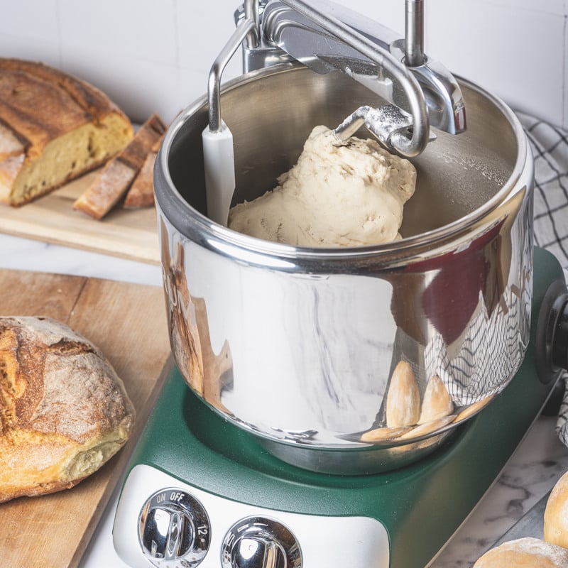 Ankarsrum assistent in forest green, sitting on top of a counter. Baking bread