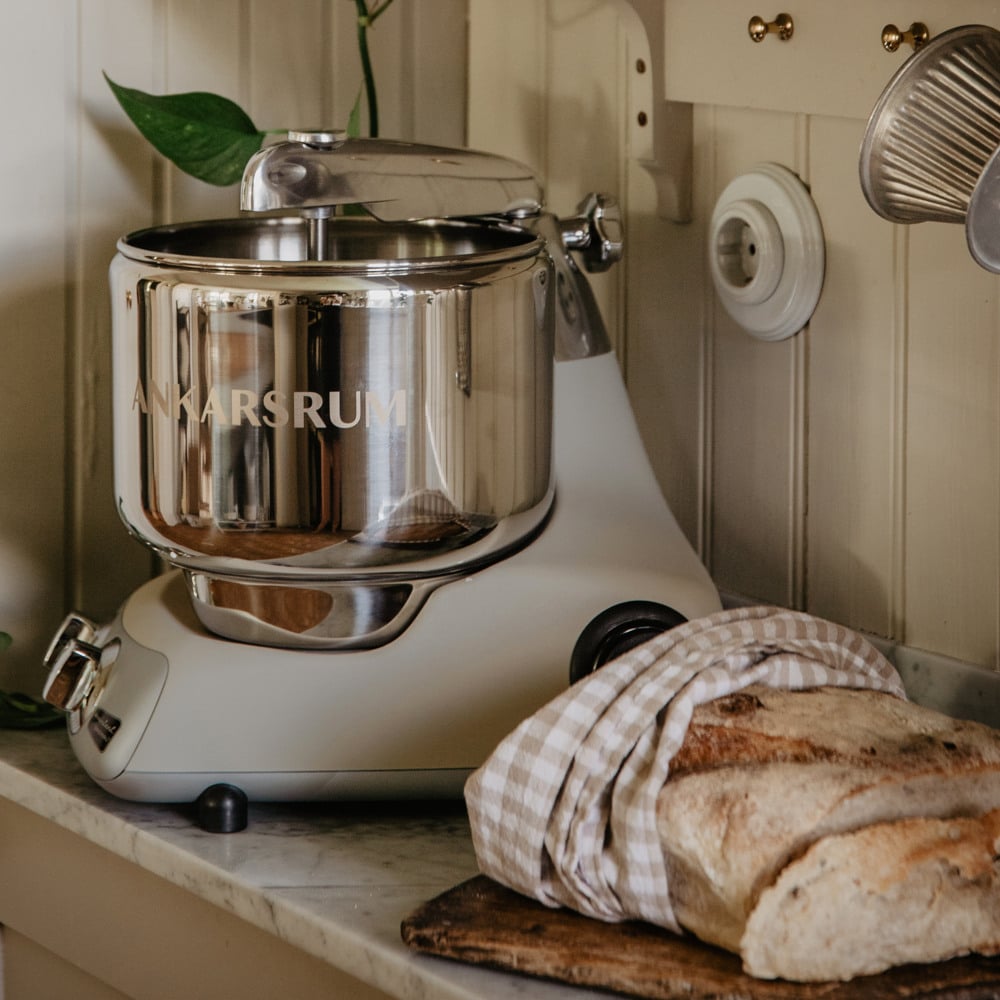 A kitchen counter with an Ankarsrum assistent and a loaf of bread on it.