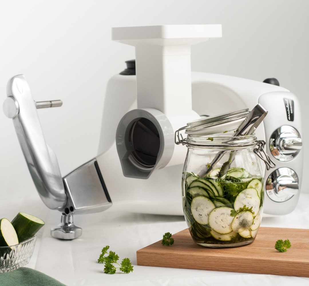 A jar filled with cucumbers next to a Ankarsrum vegetable cutter