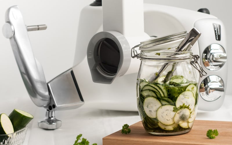 A jar filled with cucumbers next to a Ankarsrum vegetable cutter