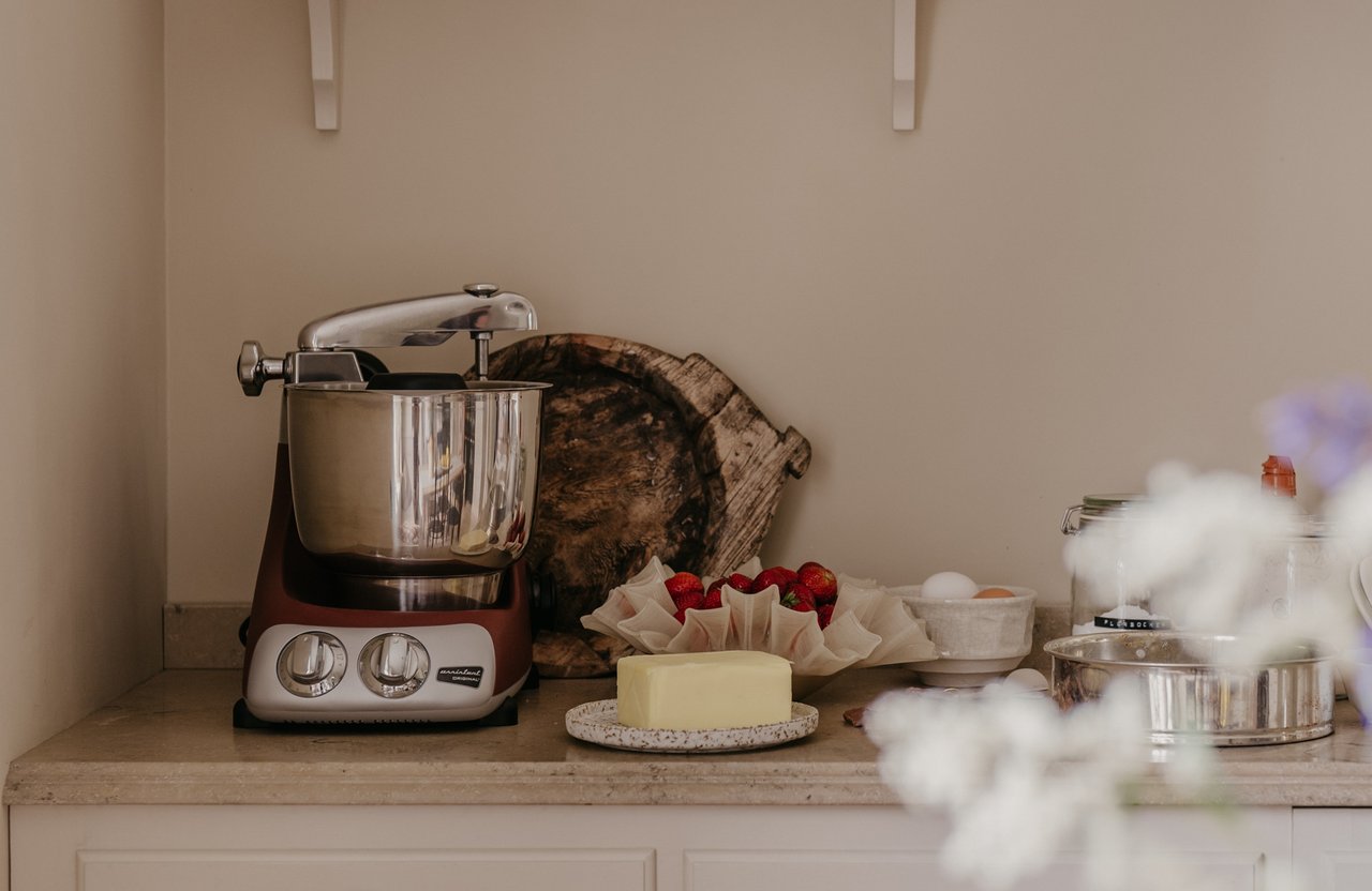A light-coloured kitchen worktop with an Ankarsrum Assistent. A plate with butter and baking accessories can be seen beside it.