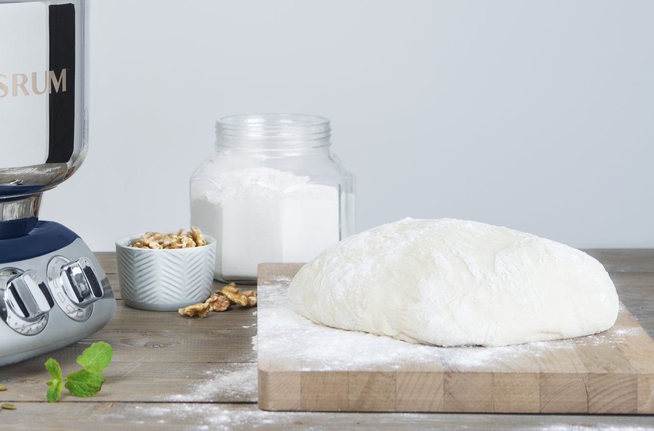 Dough resting on a wooden cutting board.