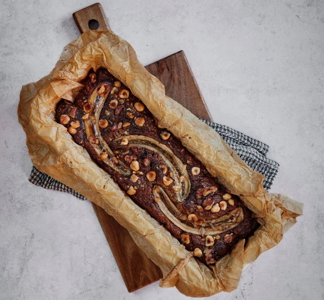 Freshly baked banana bread in a loaf pan on a kitchen counter.