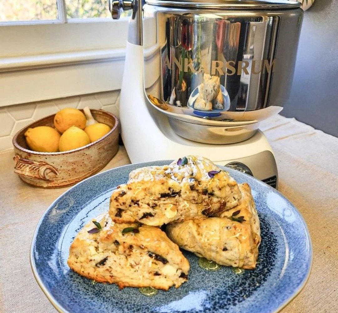 En tallrik med scones på en köksbänk. Ankarsrum assistent i bakgrunden.
