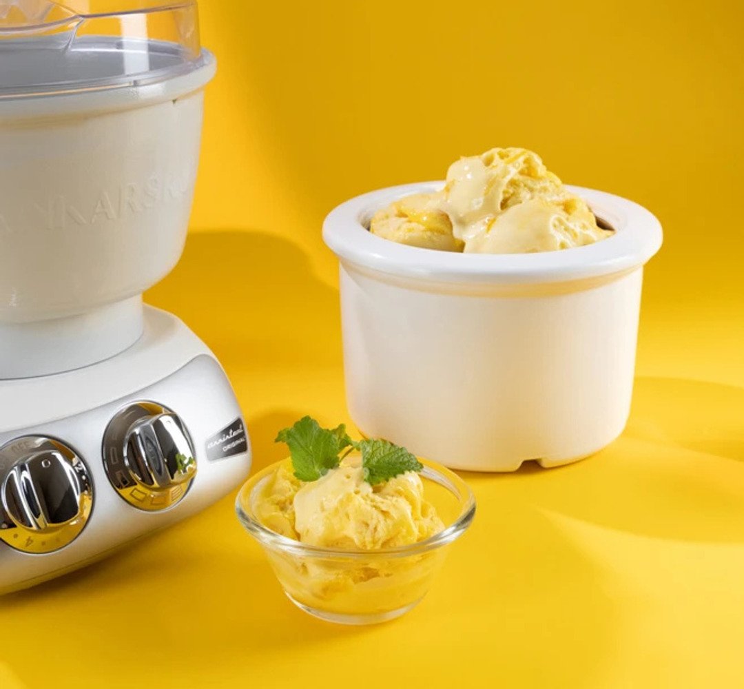 Lemon ice cream in a bowl, with an Ankarsrum ice cream maker in the background.
