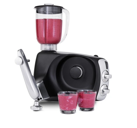Ankarsrum Assistent Original with the Blender attached, blending a smoothie, with two glasses in front.
