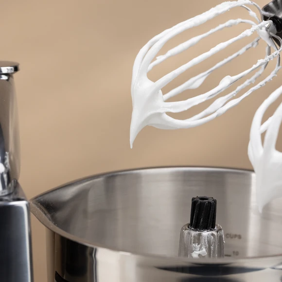 Fouet avec de la meringue dans un bol à mélanger en acier inoxydable.