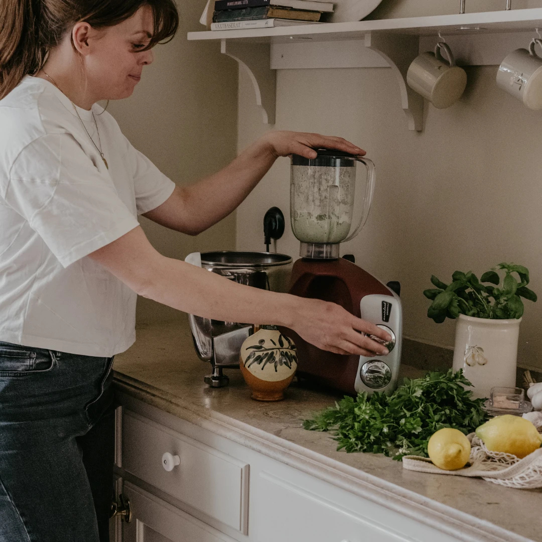Person som mixar grön smoothie med Ankarsrum-blender som del av Go Green-paketet.