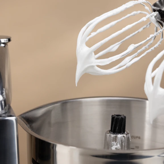 Frusta con meringa in una ciotola in acciaio inox.