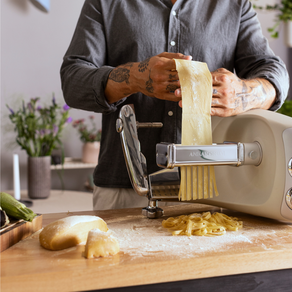 Person som använder pastavalsen till fettucine för att göra hemmagjord pasta.