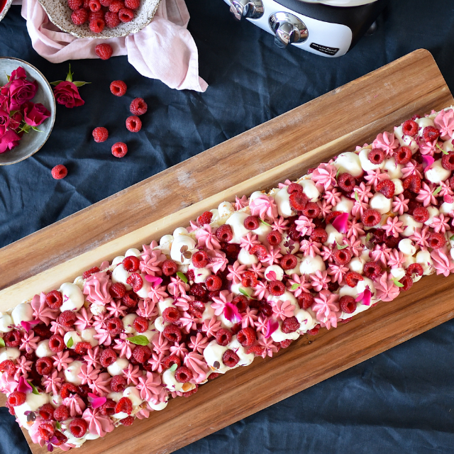 Pinocchiotårta med vispad hallonpannacotta, dekorerad med färska hallon och blommor.