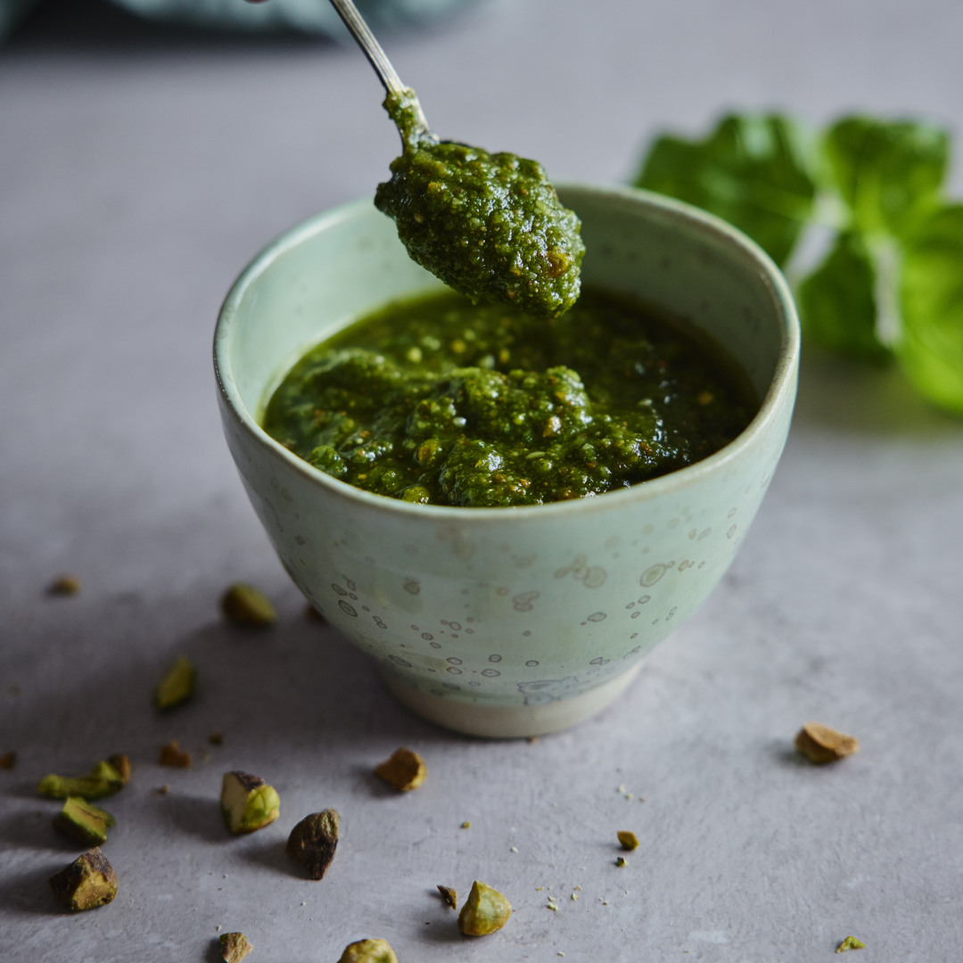 Nærbillede af en skål med hjemmelavet pesto toppet med pistacienødder.